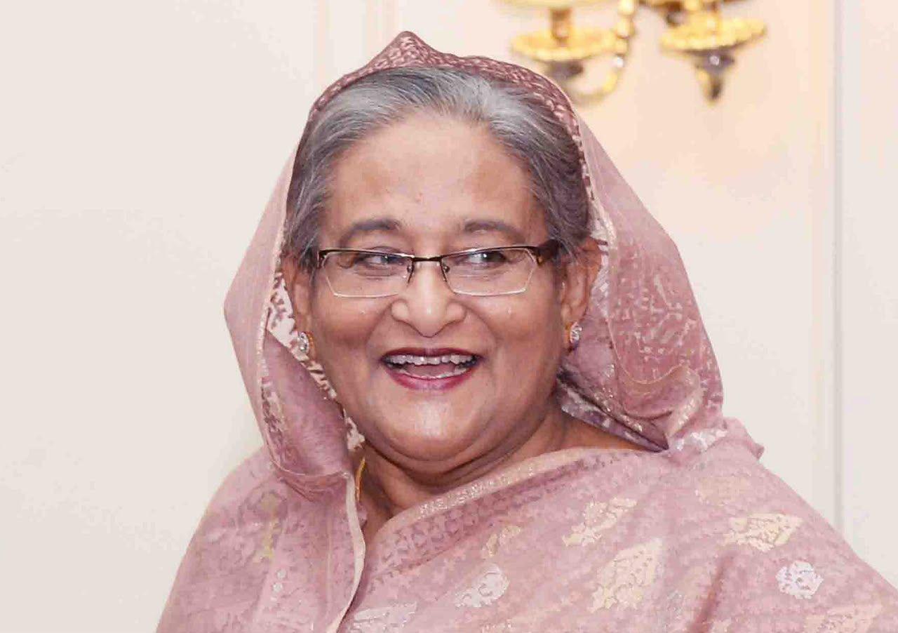 Sheikh Hasina smiling, wearing a pink sari and glasses